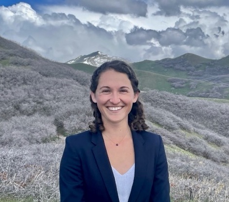 A picture of Aria Ballance smiling in front of a mountain landscape